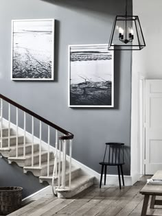 two black and white photographs hanging on the wall next to a stair case in a living room