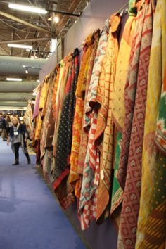 many different colored ties are on display in a room with people standing around them and looking at them