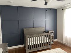 a baby's room with blue walls and wooden flooring, including a crib