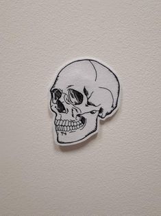 a white sticker with a black outline of a skull on it's side