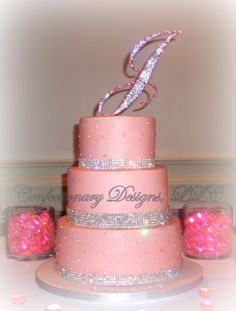 a three tiered cake with pink frosting and sparkles on it's sides