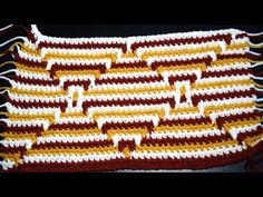 a crocheted dishcloth with brown and white stripes on the edges is laying on a black surface