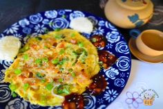 a blue and white plate topped with an omelet next to a tea pot