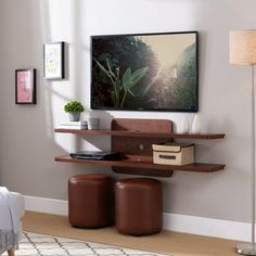 a living room with a tv mounted on the wall and two brown stools in front of it