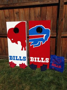 two cornhole game boards with bills and buffalo logos on them sitting in the grass