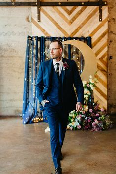 a man in a blue suit and tie walking down the aisle to his wedding ceremony