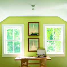 a laptop computer sitting on top of a wooden table in front of two large windows