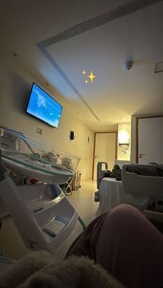 a person laying in a hospital bed with a flat screen tv on the wall above them