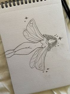 a drawing of a fairy sitting on top of a bed next to a black pen