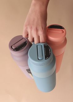 a person holding onto three different colored cups