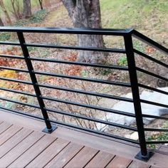 there is a dog that is standing on the deck looking out at the trees and grass