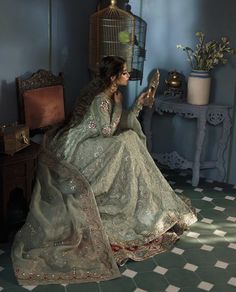 a woman is sitting on a chair with a birdcage in her hand and reading