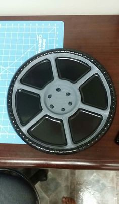 a wooden table topped with a black and white film reel on it's side