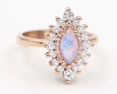 an opal and diamond cluster ring in yellow gold, with white diamonds surrounding it