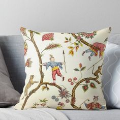 a decorative pillow on a couch with an animal and tree pattern in yellow, red, blue, green and white