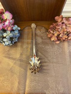 a silver spoon sitting on top of a table next to some pink and blue flowers