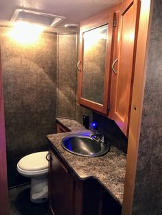 a bathroom with a sink, toilet and mirror in it's stall area at night