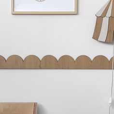 a clock mounted to the side of a white wall next to a wooden table and chair