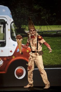 a man dressed as a zombie standing in front of a food truck with his hands out