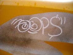 graffiti written on the side of a yellow vehicle with white writing that says pops in it