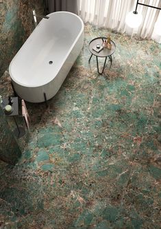 a bath tub sitting on top of a green floor next to a table and chair