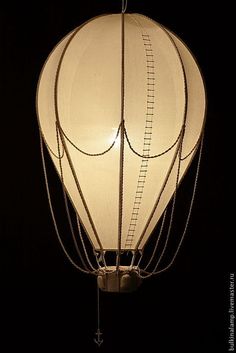 a lit up white hot air balloon in the dark with chains hanging from it's side