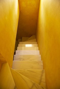 the stairs are lined with yellow walls and white steps leading up to an open door