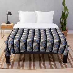 a bed with a blue and white blanket on top of it next to a potted plant