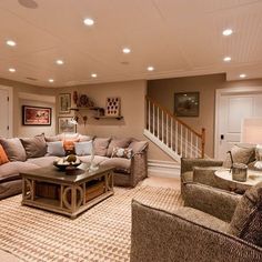 a living room filled with lots of furniture and a stair case in the back ground