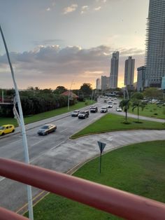 cars are driving down the road in front of tall buildings at sunset or sunrise time