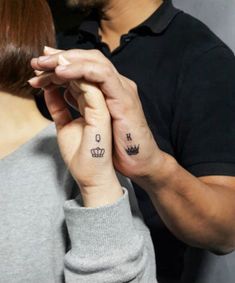 a man and woman holding each other's hands with small tattoos on their fingers