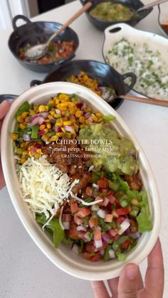 a person holding up a bowl filled with food on top of a white countertop