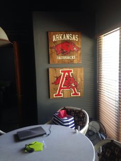 two wooden signs hang on the wall above a round table in a room with chairs