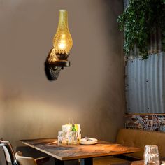 a dining room table with two chairs and a lamp on the wall above it that is lit up