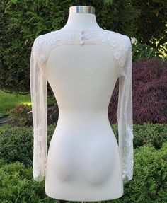 a mannequin wearing a white dress with sheer sleeves