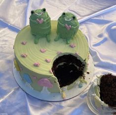 there is a cake with two green frogs on it and one has a hole in the middle