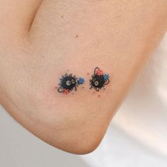 two spider tattoos on the back of a woman's left arm, both with blue and red sprinkles