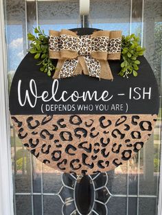 a welcome sign hanging on the front door with leopard print and ribbon around it's edges