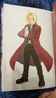 a hand holding an open book with a drawing of a man in a red coat and black pants