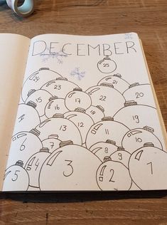 an open notebook with numbers and faces drawn in it on top of a wooden table