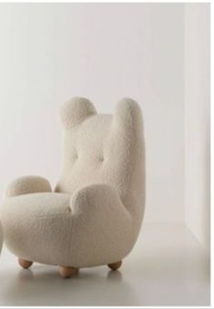 a chair and ottoman made out of wool with wooden legs in front of a white wall