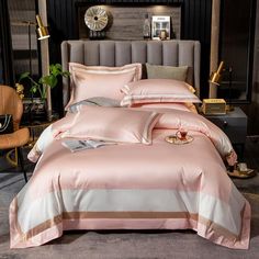 a bed with pink sheets and pillows in a room next to a chair, table and clock