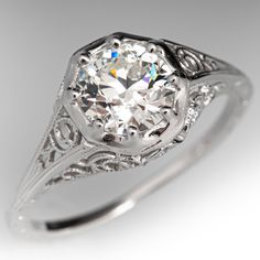 an antique style diamond ring with filigrees on the band and center stone