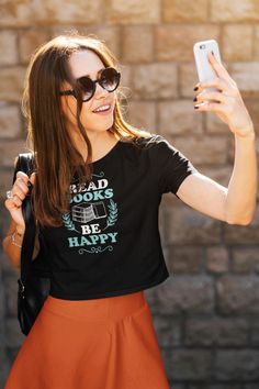 a woman taking a selfie with her cell phone while wearing a t - shirt with hearts on it