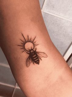 a tattoo on the arm of a woman with a bee in it's center