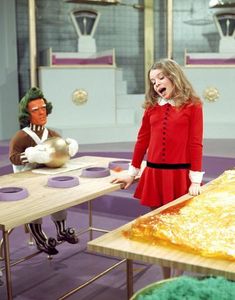 a woman in a red dress standing next to a table with doughnuts on it