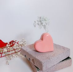 a heart shaped vase sitting on top of a cement block