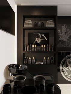 a black and white room with shelves filled with bottles, plates and cups on the table