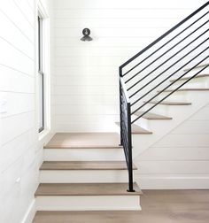 there is a black hand rail on the stairs in this house with white walls and wood flooring