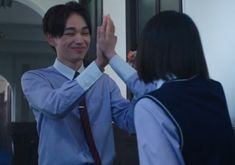 a man and woman high fiving each other in front of a mirror with their hands together